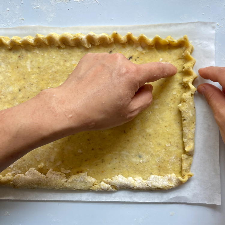 Image of Going around the edges of the dough, crimp the dough between your two forefingers and thumb as you would a classic pie crust.